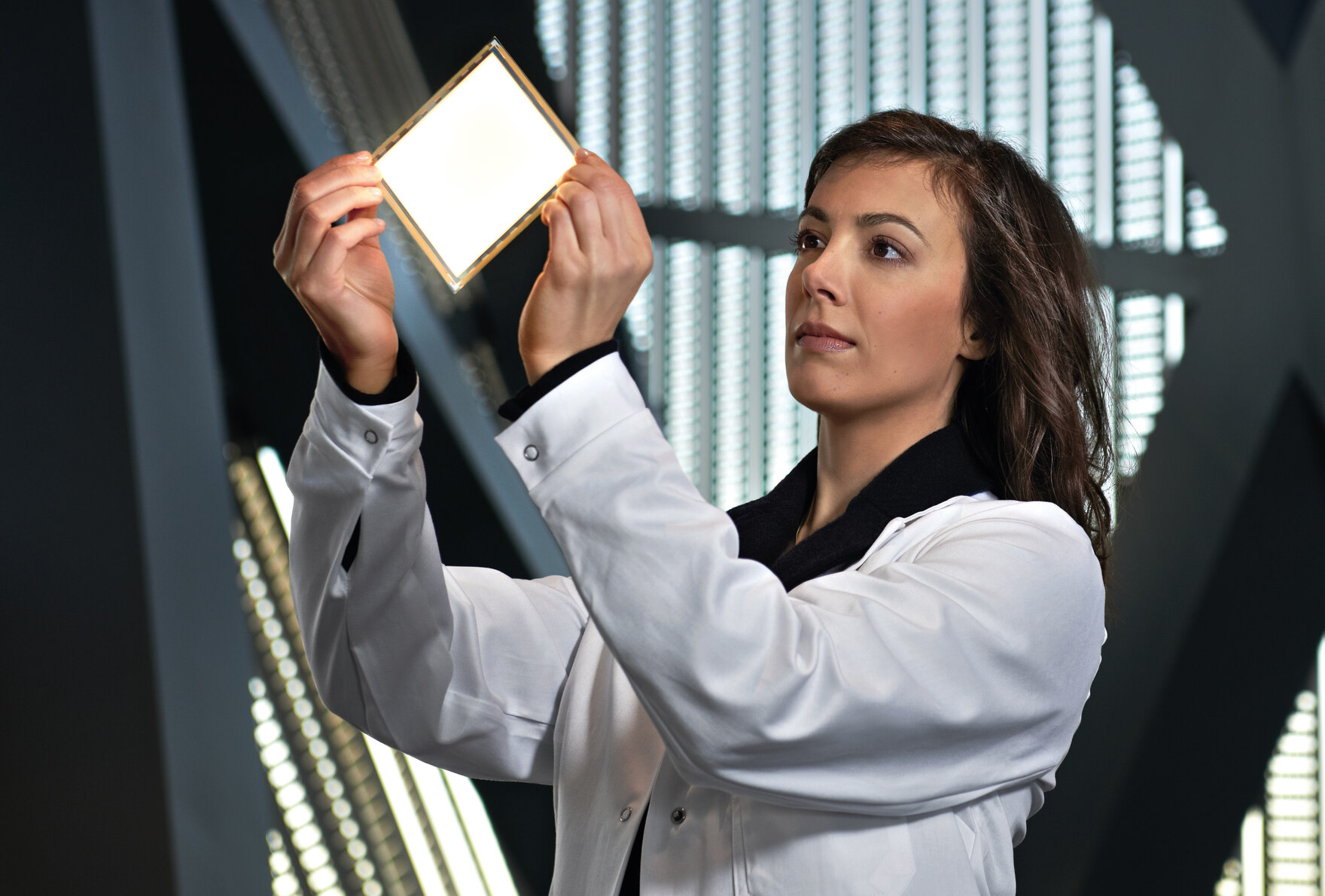 Eine Wissenschaftlerin im weißen Kittel prüft ein Material